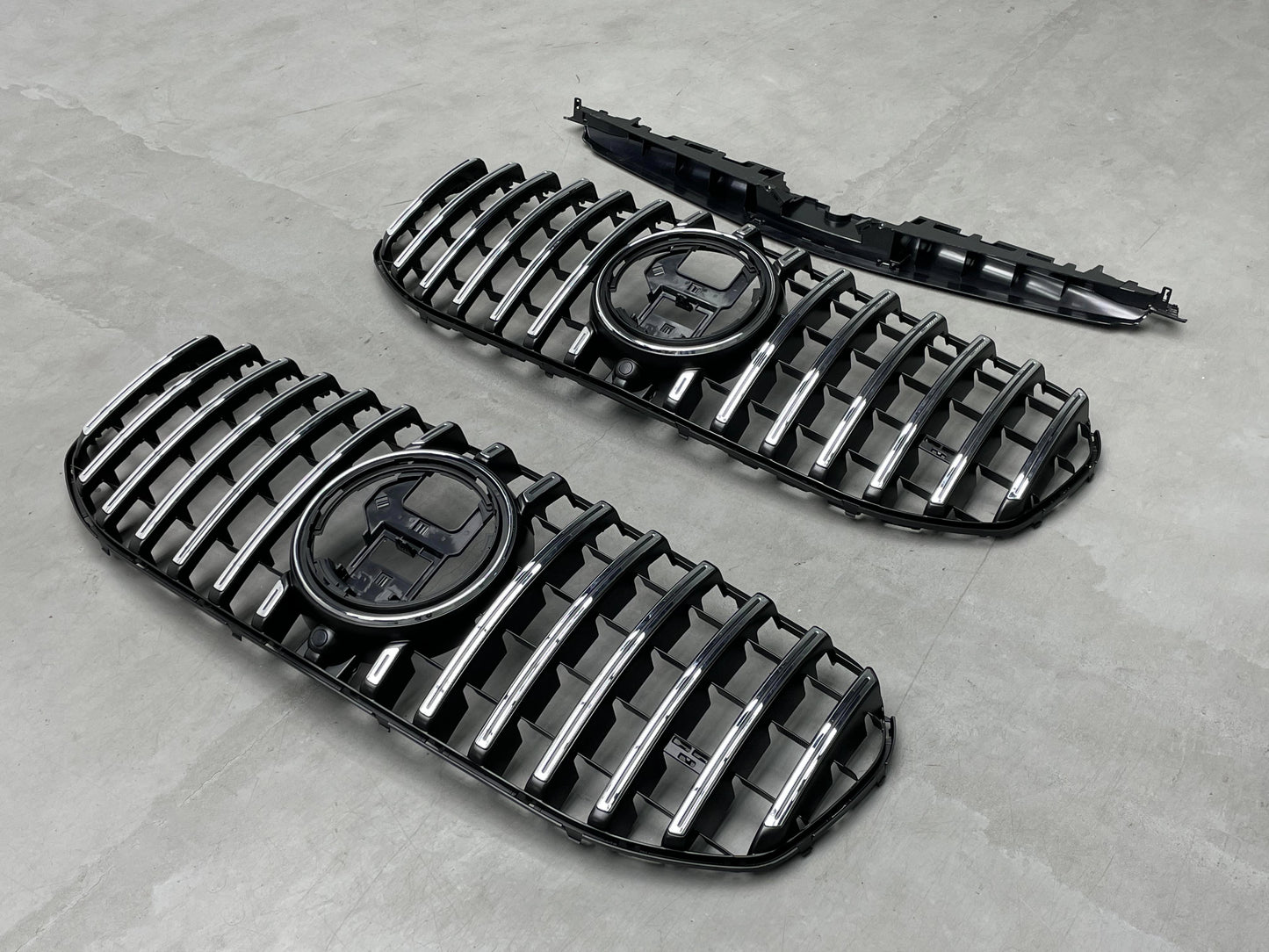 Angled view of the direct replacement AMG Panamericana front grille assembly for Mercedes GLS450 and GLS580 X167, showcasing the mounting tabs and sensor cutouts.
