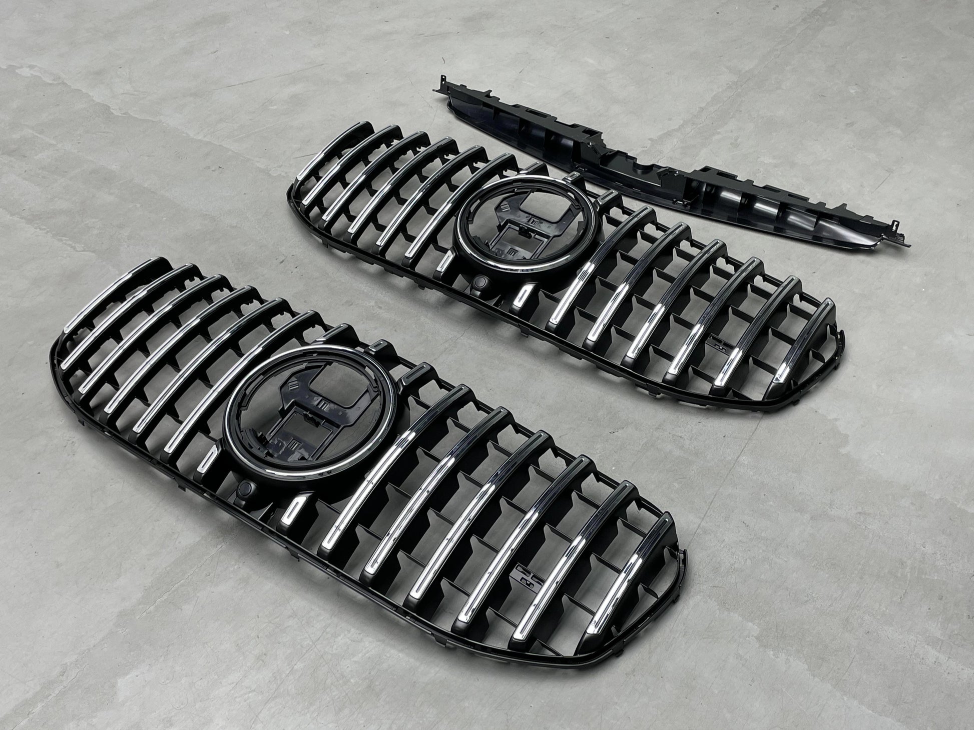 Angled view of the direct replacement AMG Panamericana front grille assembly for Mercedes GLS450 and GLS580 X167, showcasing the mounting tabs and sensor cutouts.