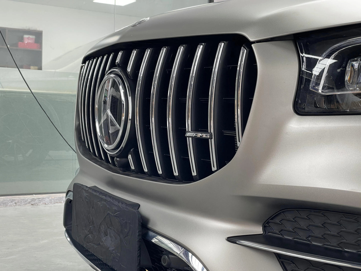 Close-up side view of the AMG GT Panamericana front grille installed on a 20-23 Mercedes GLS450 X167, highlighting the large curvature design and chrome vertical slats.